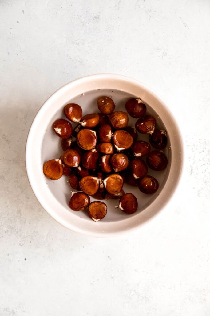 scored raw chestnuts soaking in water.