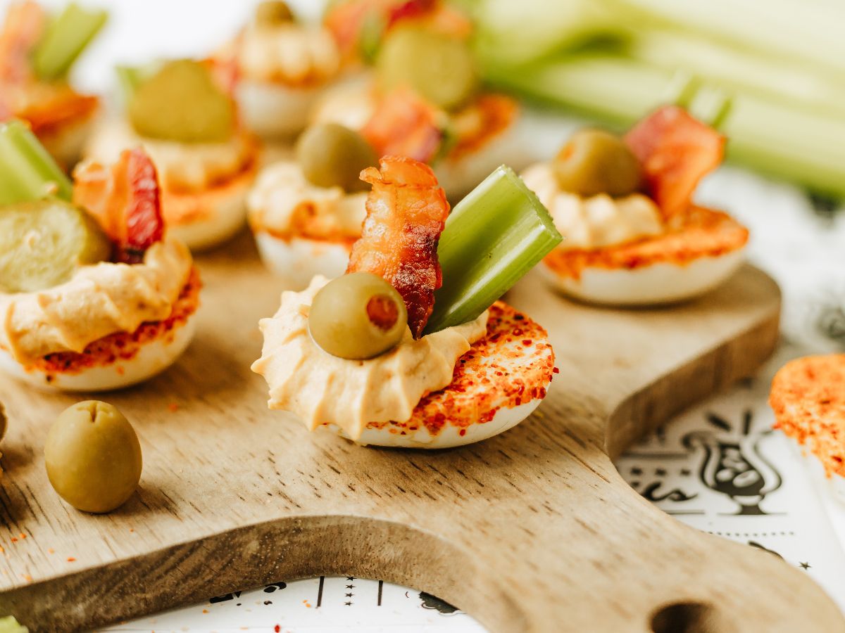 horizontally framed hero shot of a wooden serving tray filled with bloody mary deviled eggs.