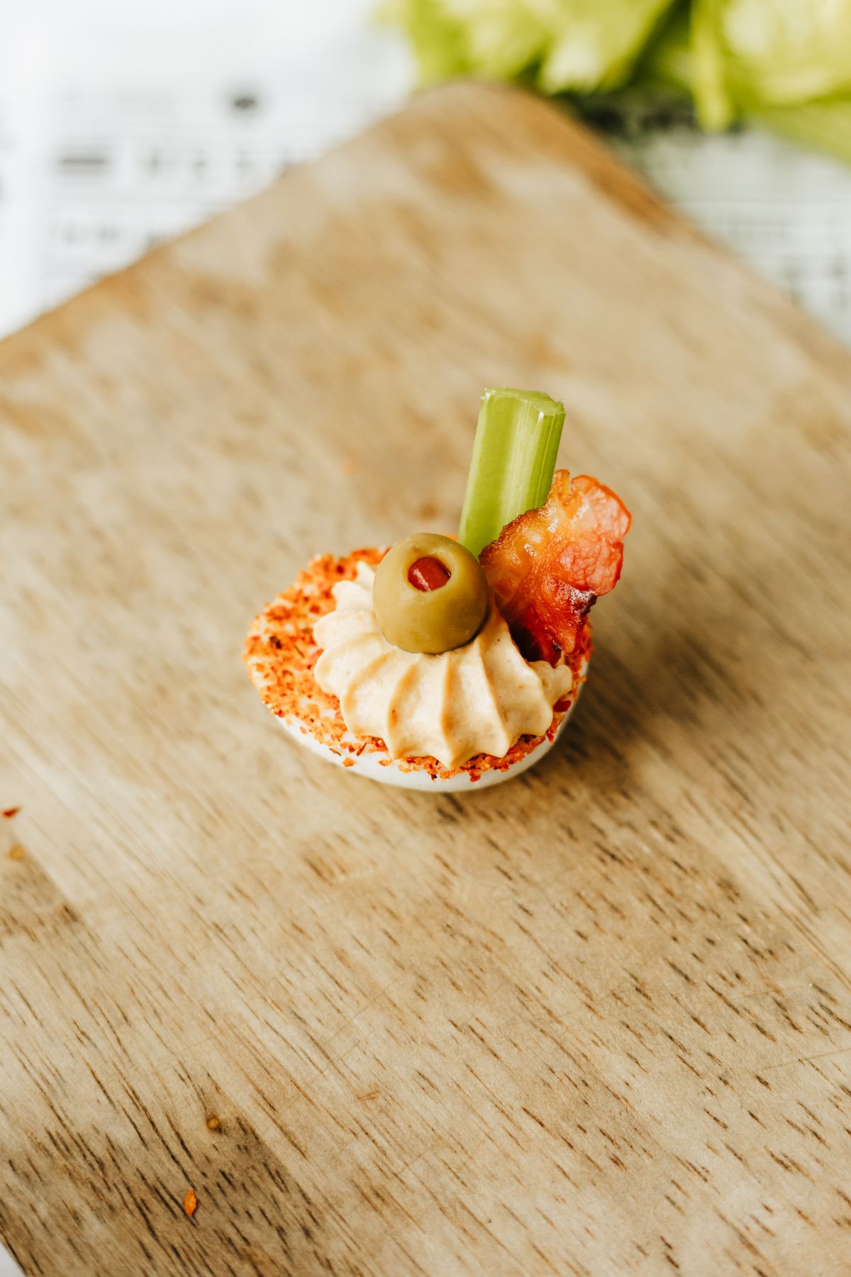garnished bloody mary deviled egg on a wooden tray.
