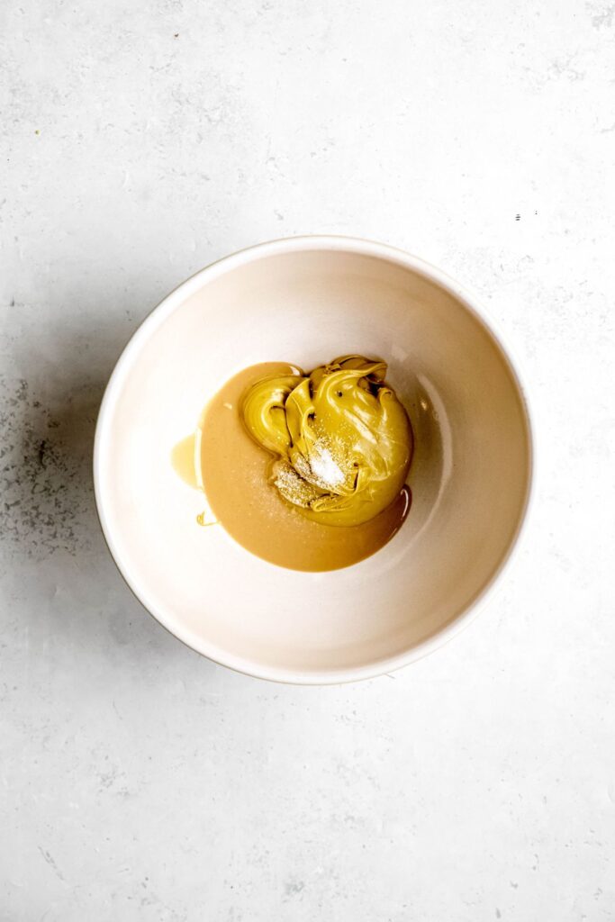 tahini and pistachio cream added to a white mixing bowl.