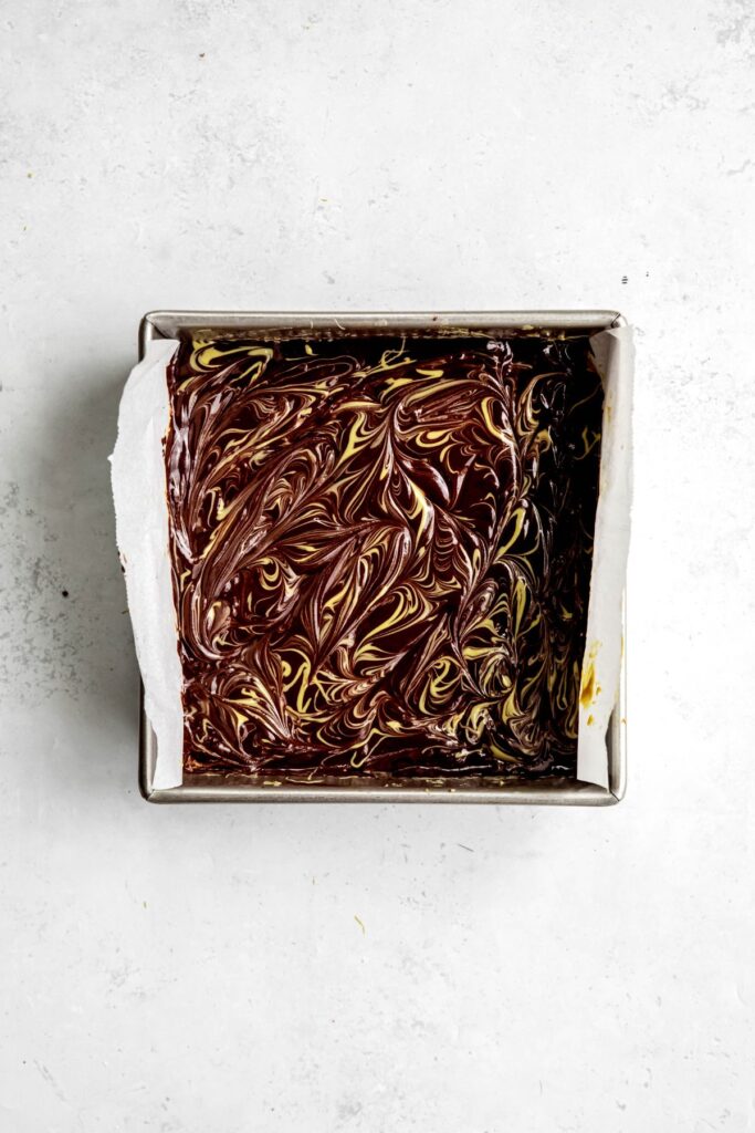 chocolate ganache with pistachio cream on top of the pistachio mixture after swirling.