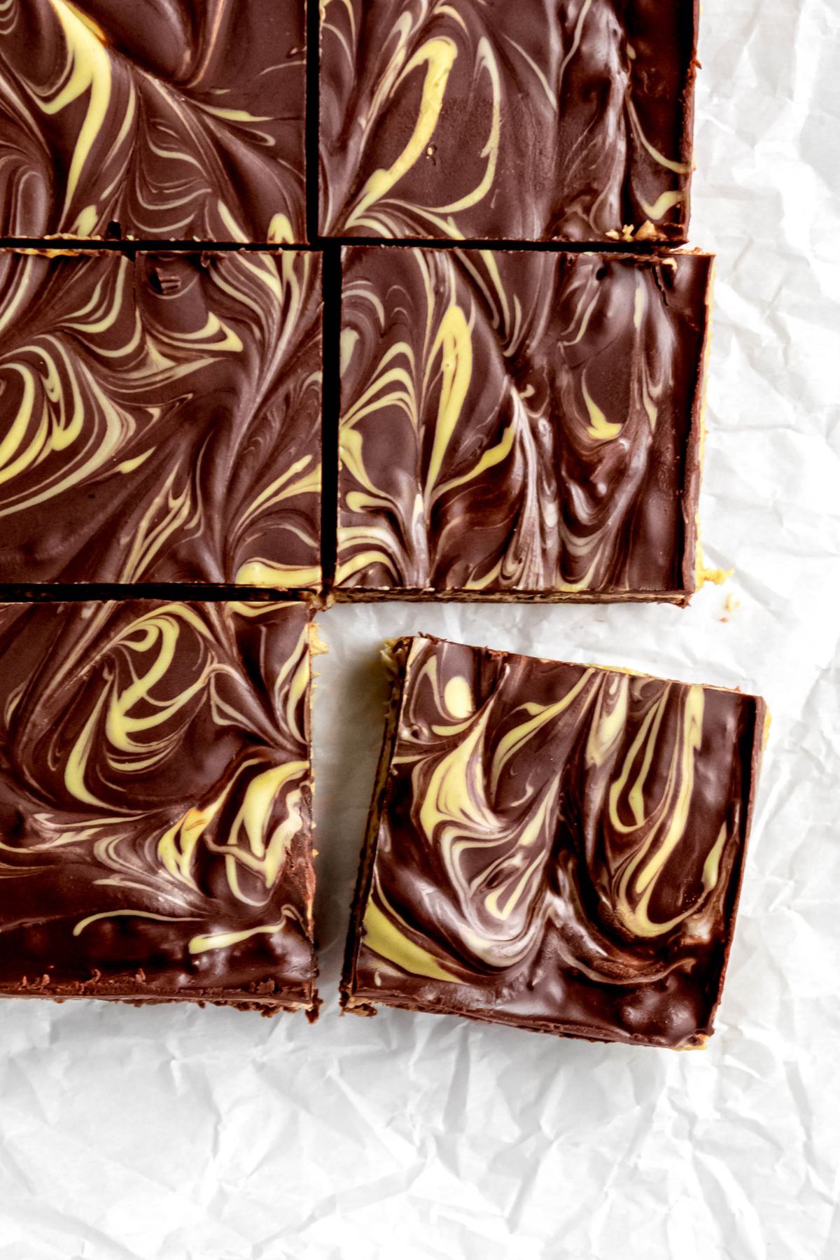 closeup overhead shot of the right hand of a tray of dubai chocolate brownies with the bottom right corner piece slightly pulled away.