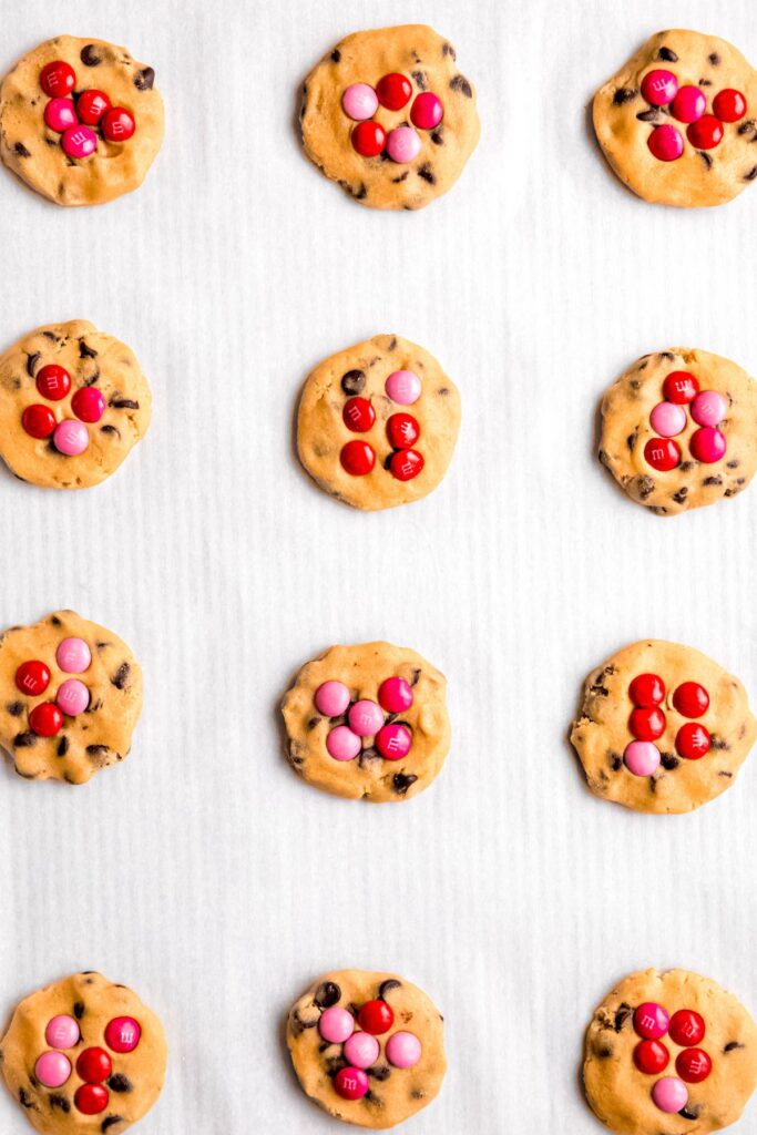 red and pink M&Ms added to the tops of the raw cookies.