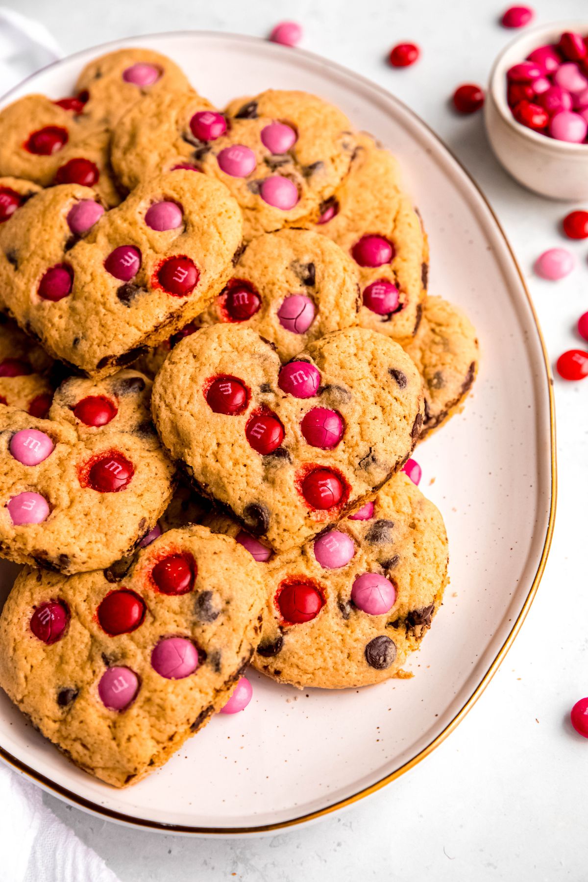 overhead shot of an oval white earthenware serving platter filled with heart-shaped chocolate chip cookies.