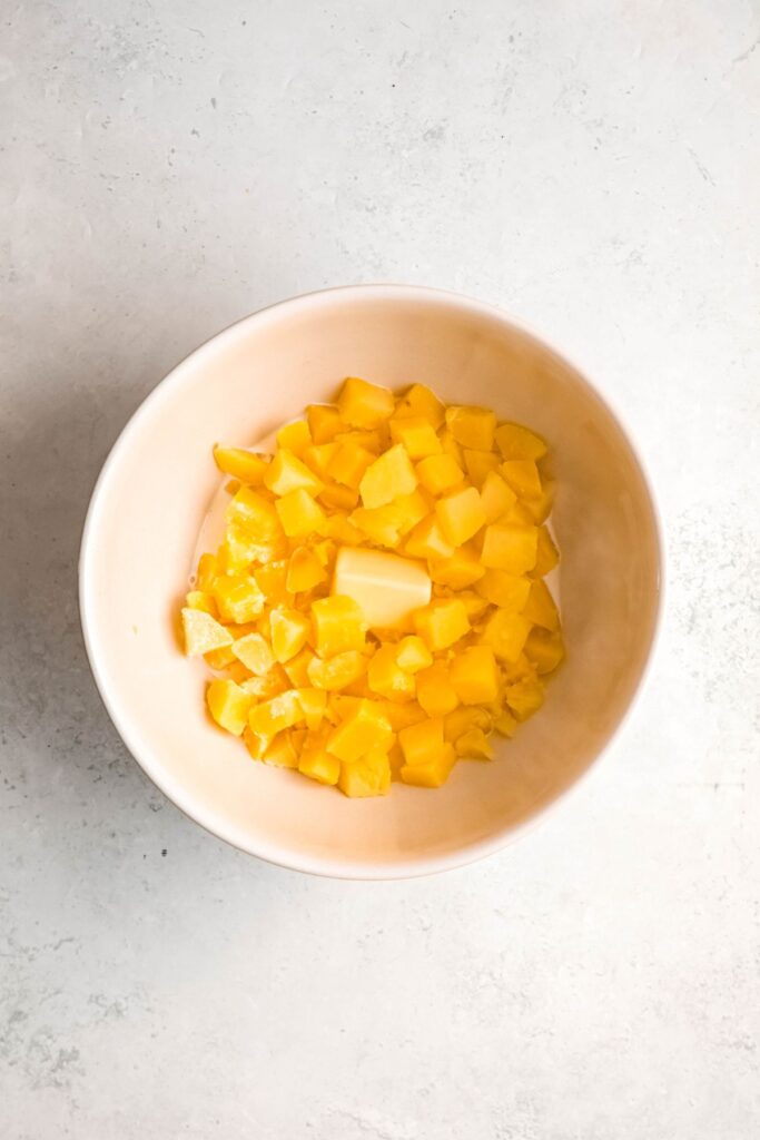 Cooked potatoes in a mixing bowl with butter.