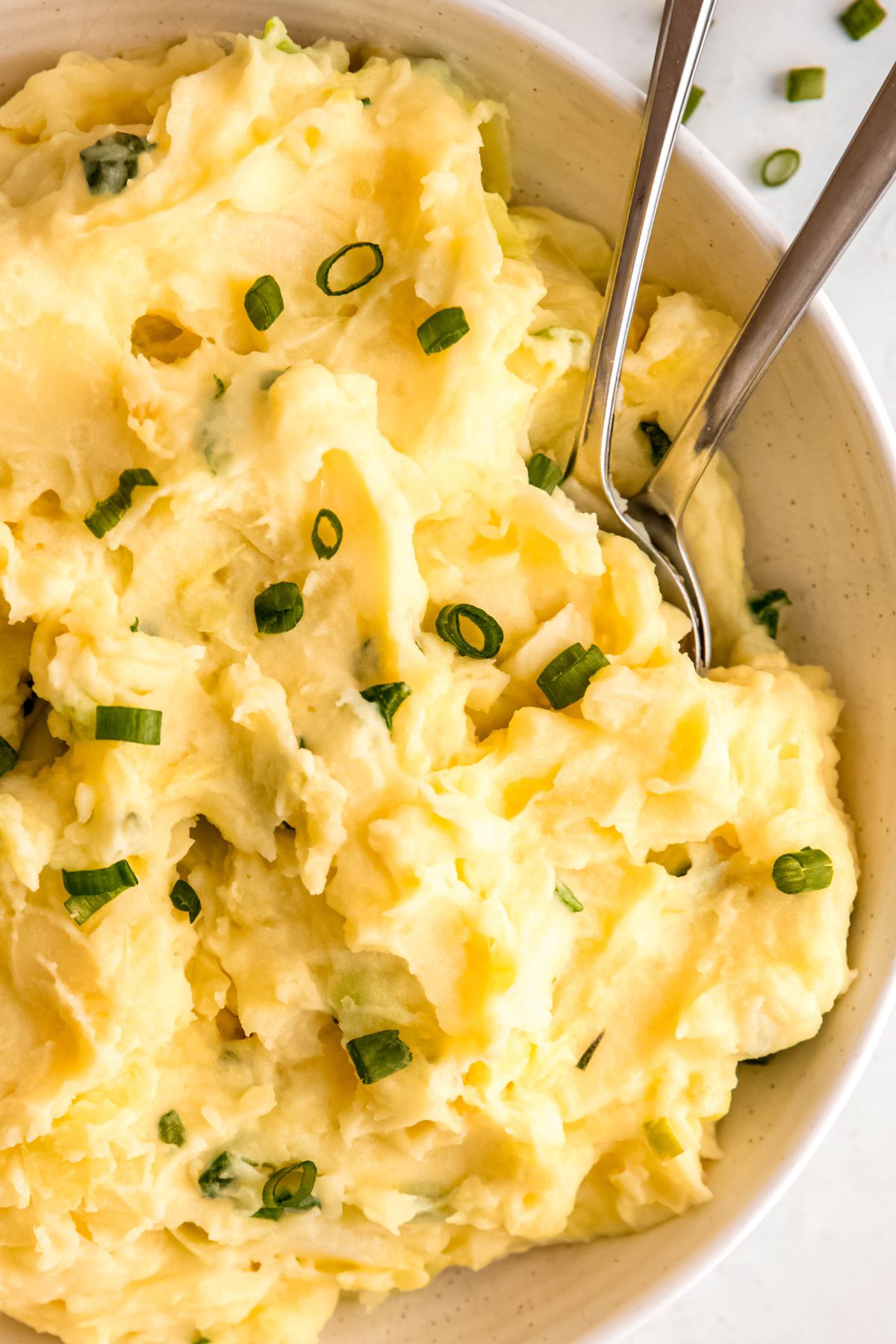 A close-up overhead shot of a bowl of colcannon with two serving spoons in it.