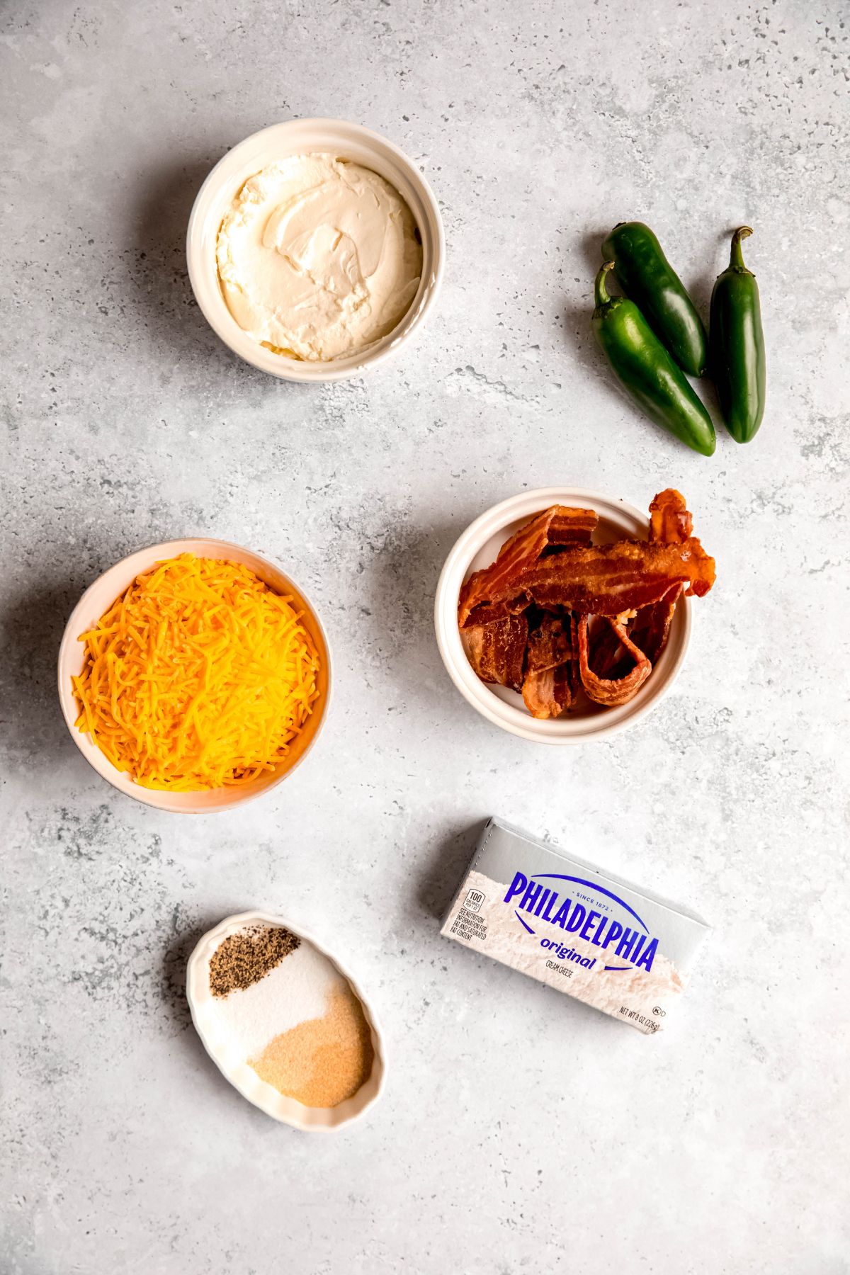 ingredients needed to make easy jalapeno popper dip recipe measured out on a white table.