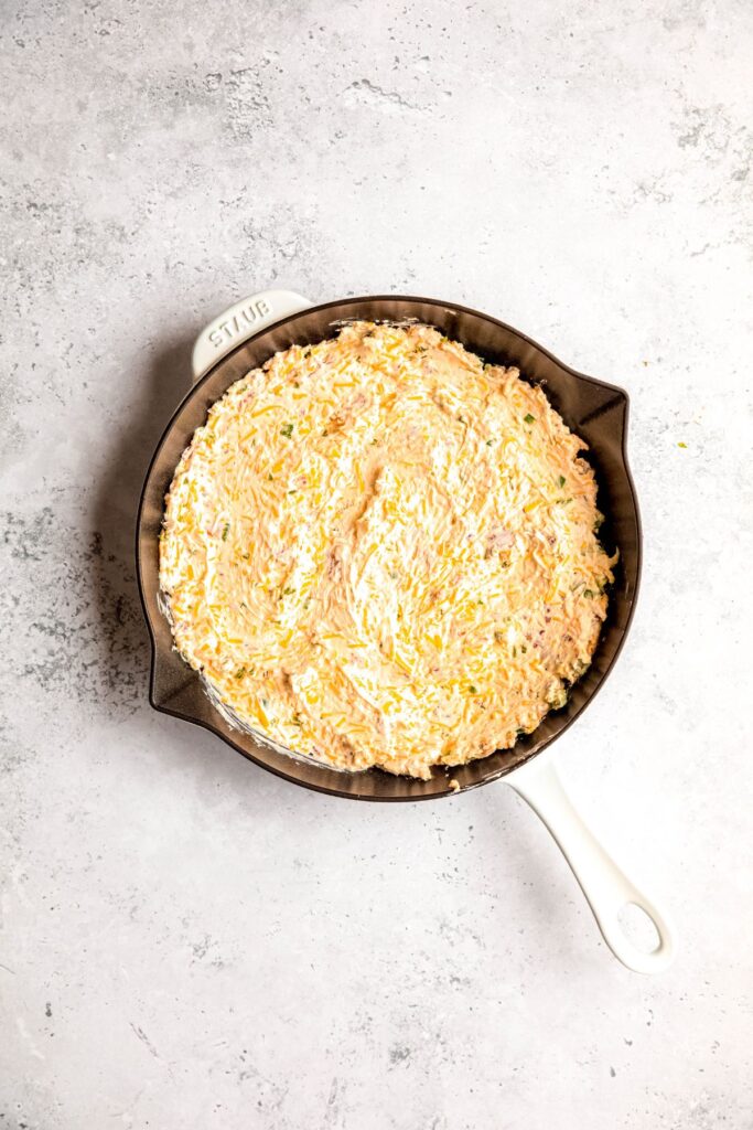 jalapeño popper dip after spreading out in a cast iron skillet.