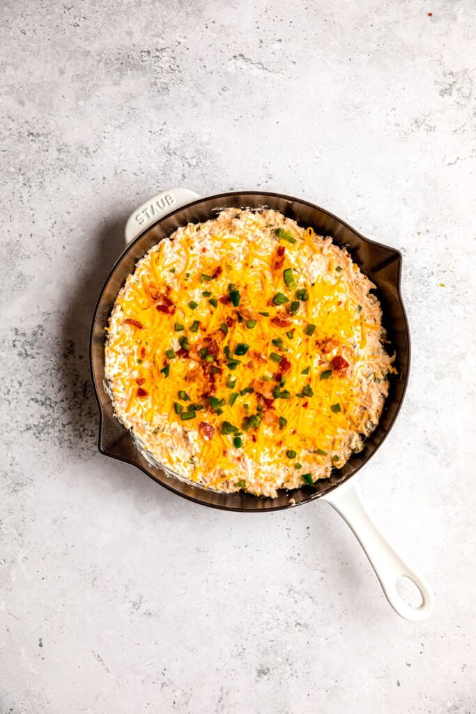 remaining cheese, bacon, and fresh jalapeños sprinkled on top of the popper dip before baking.