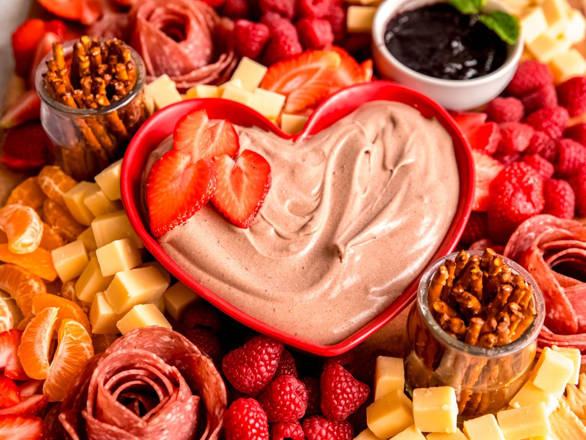 A close-up angled shot of the bowl of chocolate fruit dip, surrounded by pretzels, fruit, salami roses, and cheese.