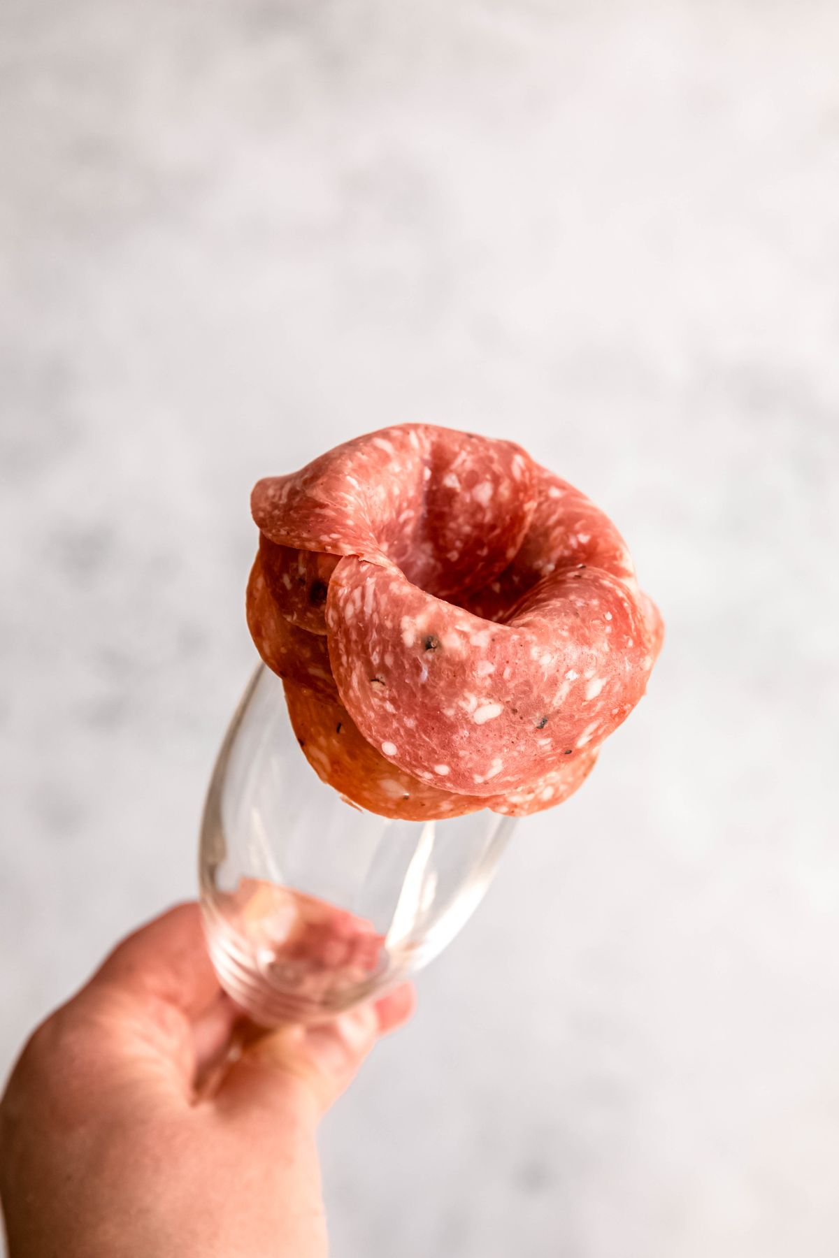 A close-up shot of a salami rose assembled on a champagne flute.