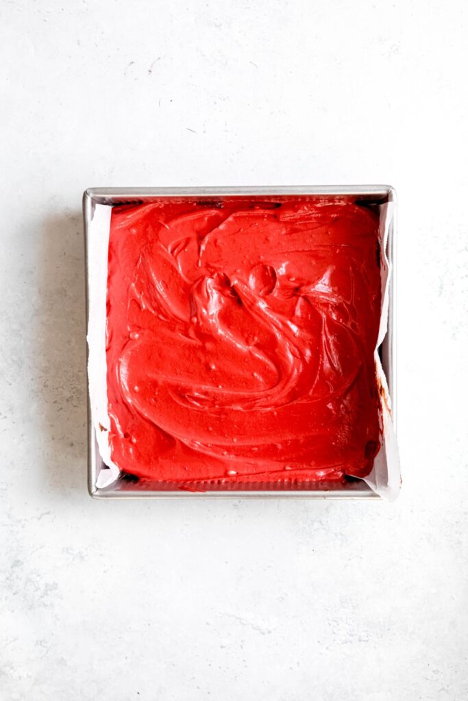 red velvet cheesecake layer spread out over the brownie batter.
