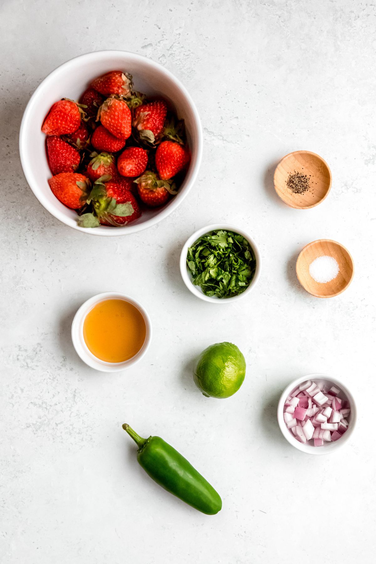 ingredients needed to make strawberry pico de gallo salsa recipe measured out on a white table.
