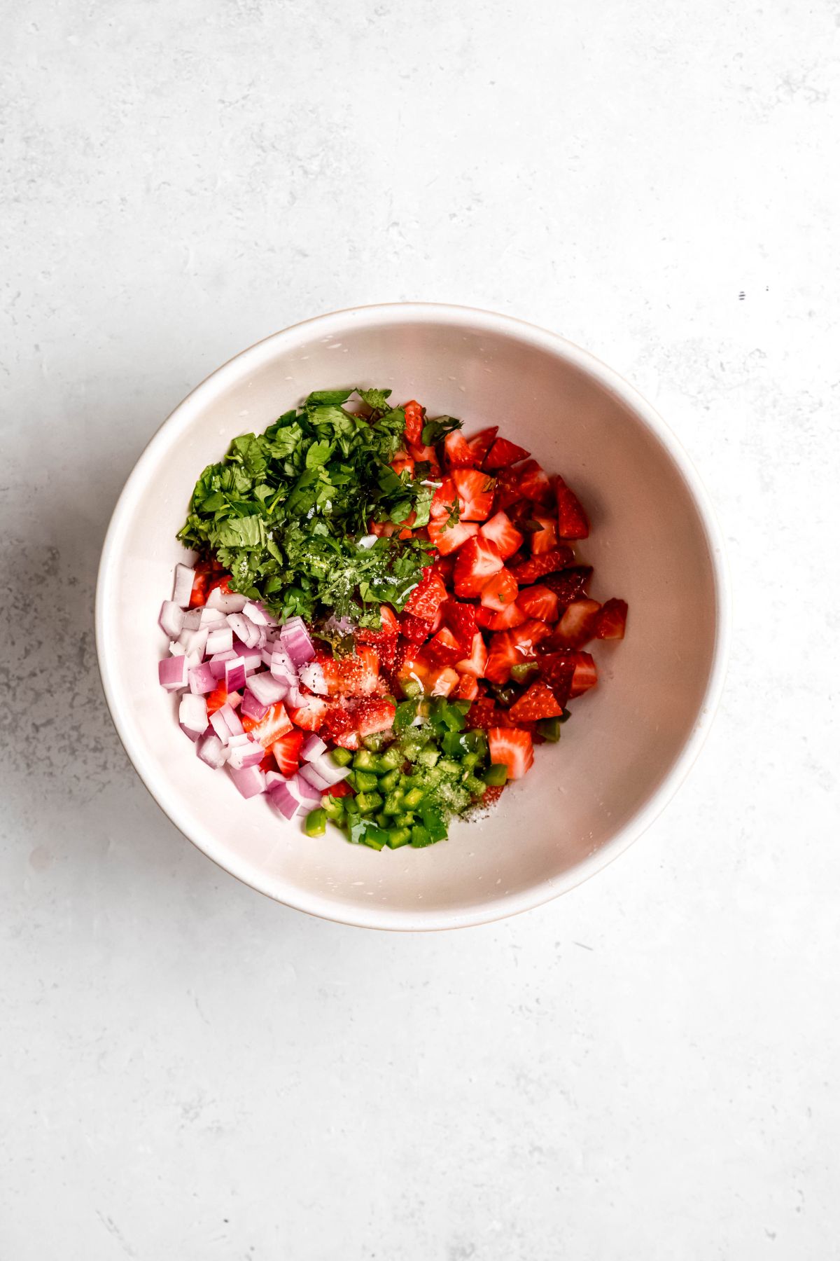 all strawberry salsa ingredients added to a bowl.