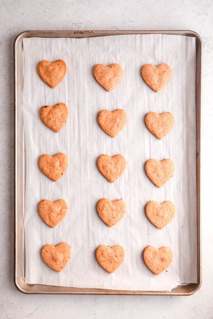 raw strawberry shortbread hearts on a parchment lined cookie sheet to freeze.