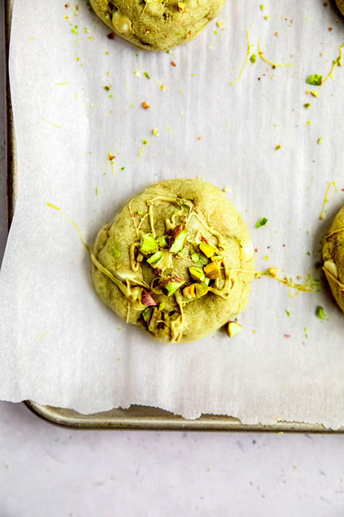 closeup overhead shot of a baked stuffed pistachio cookie after drizzling with extra pistachio cream and sprinkled with chopped pistachios.