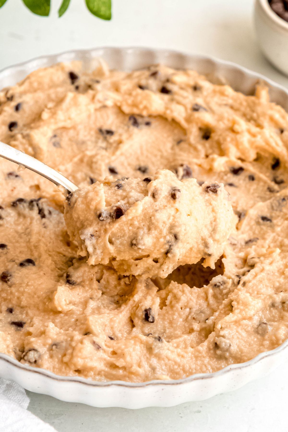 closeup shot of a silver spoon taking a bite of cottage cheese edible cookie dough from the serving bowl.