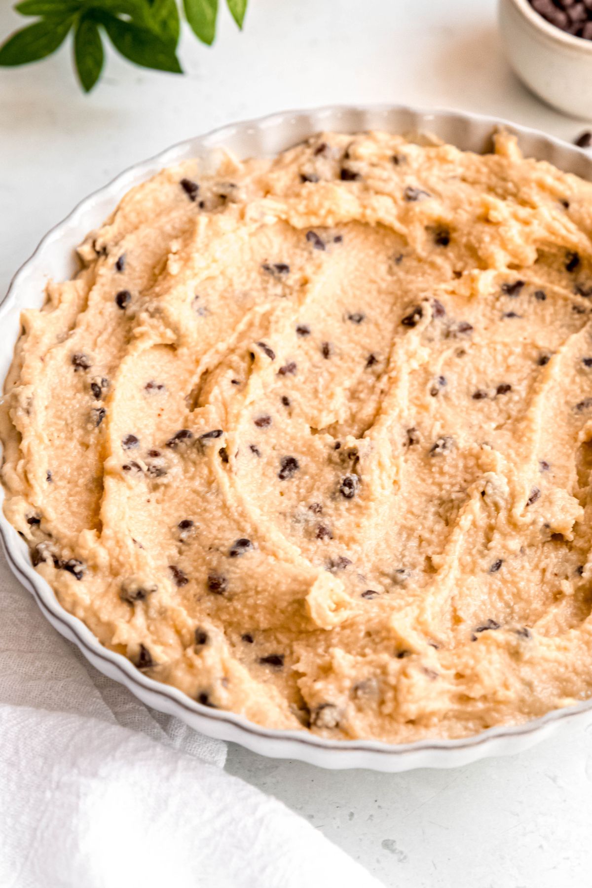 scalloped white serving bowl filled with creamy cottage cheese edible cookie dough with mini chocolate chips.
