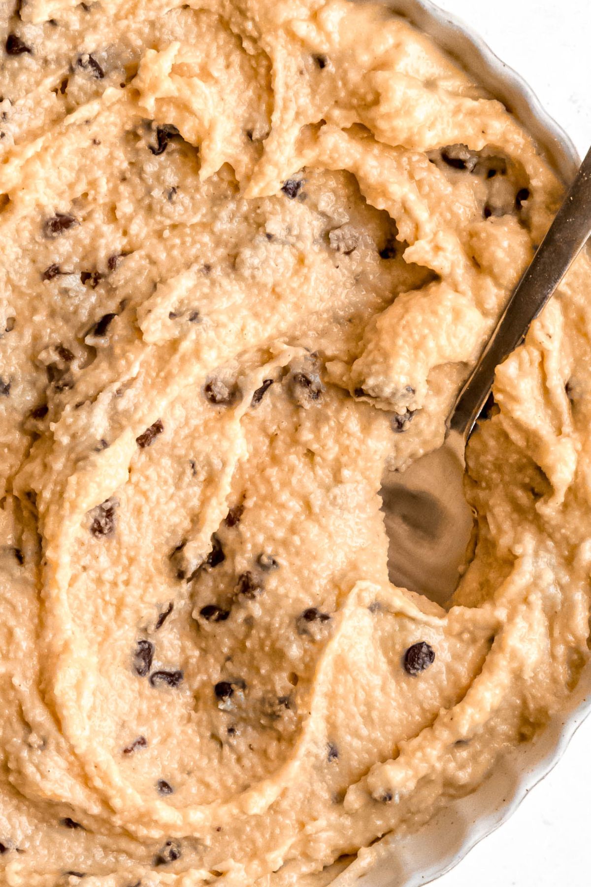 closeup overhead shot of cottage cheese cookie dough in a white bowl with a silver spoon.