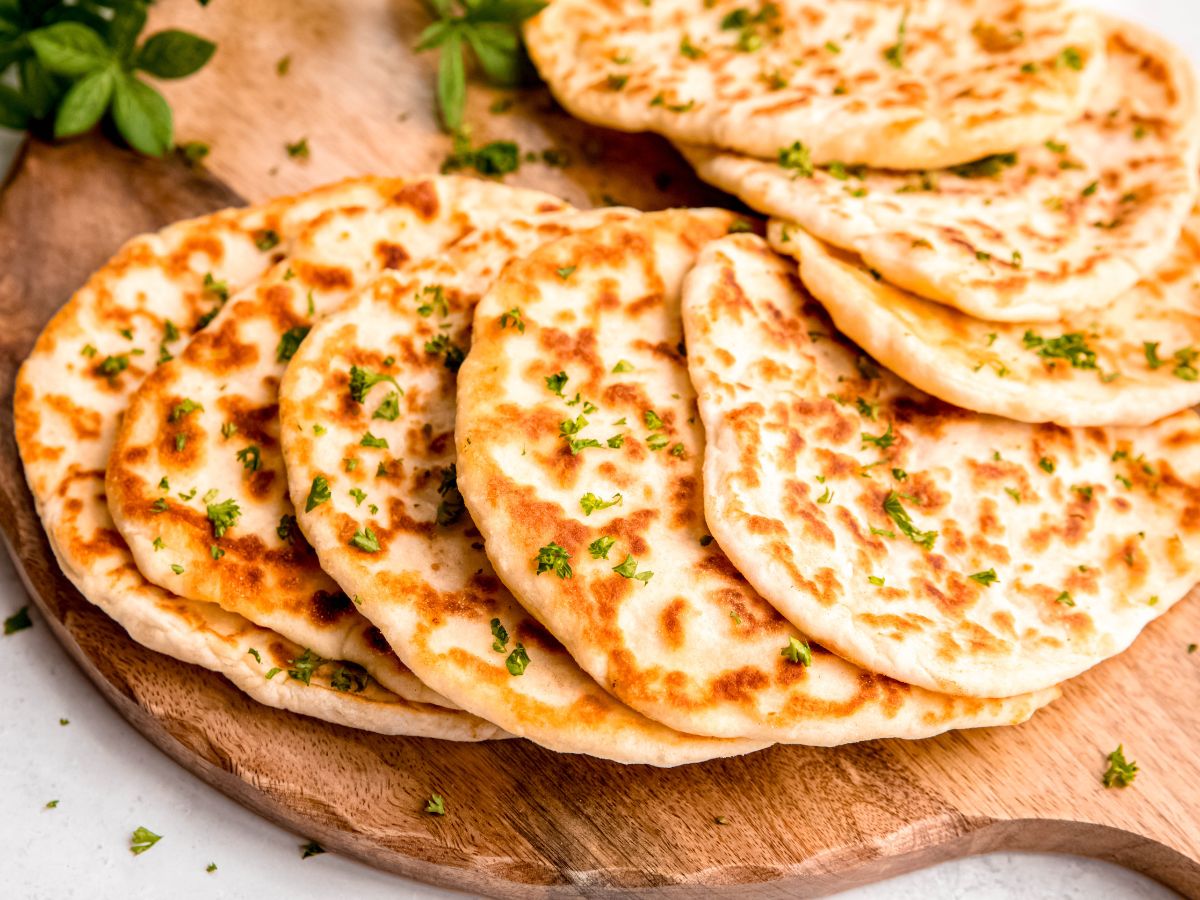 horizontally framed hero shot of cottage cheese flatbreads spread out in a semicircle on a wooden board.