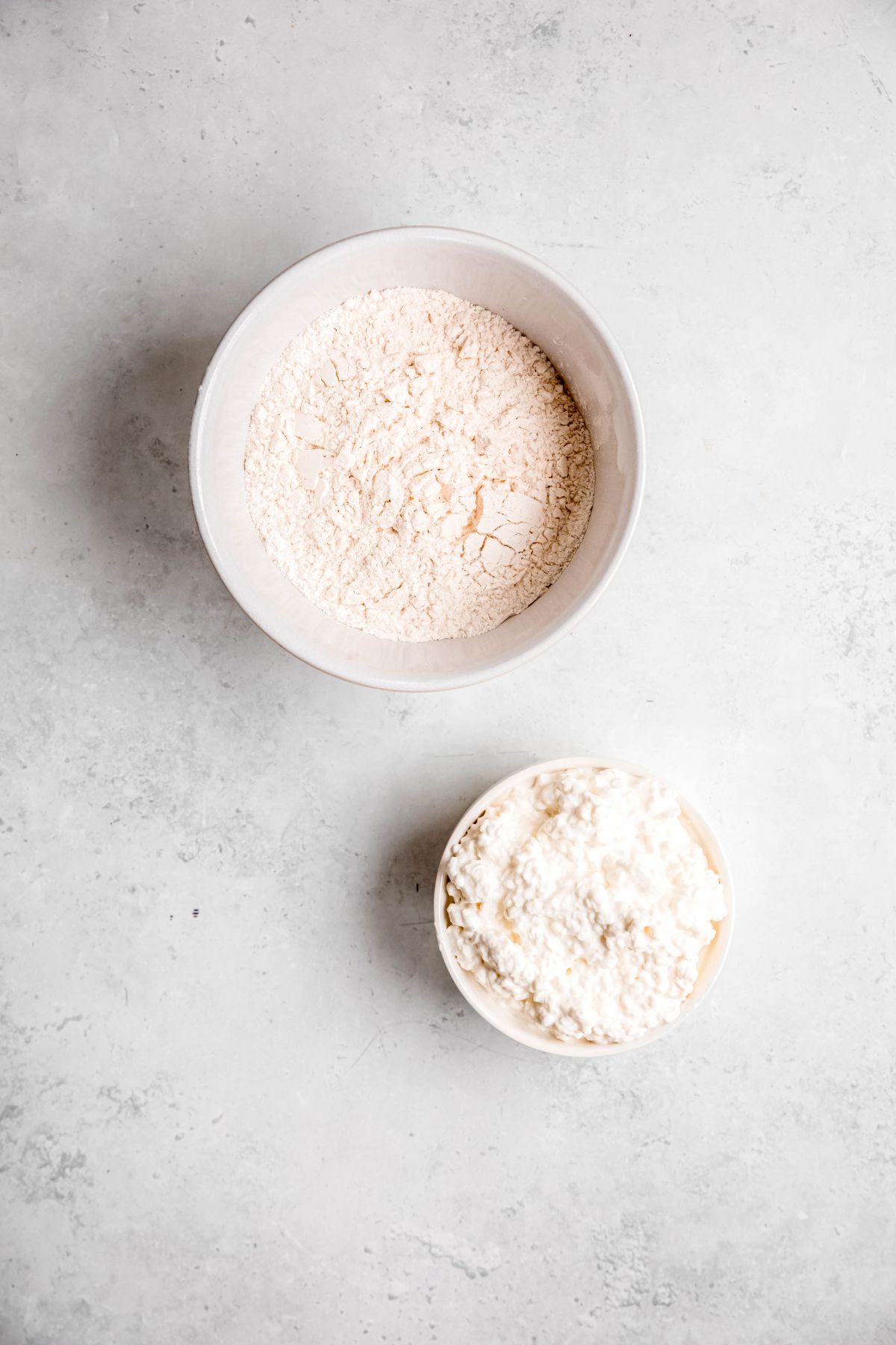 cottage cheese and self rising flour measured out on a white table for making cottage cheese flatbread recipe.