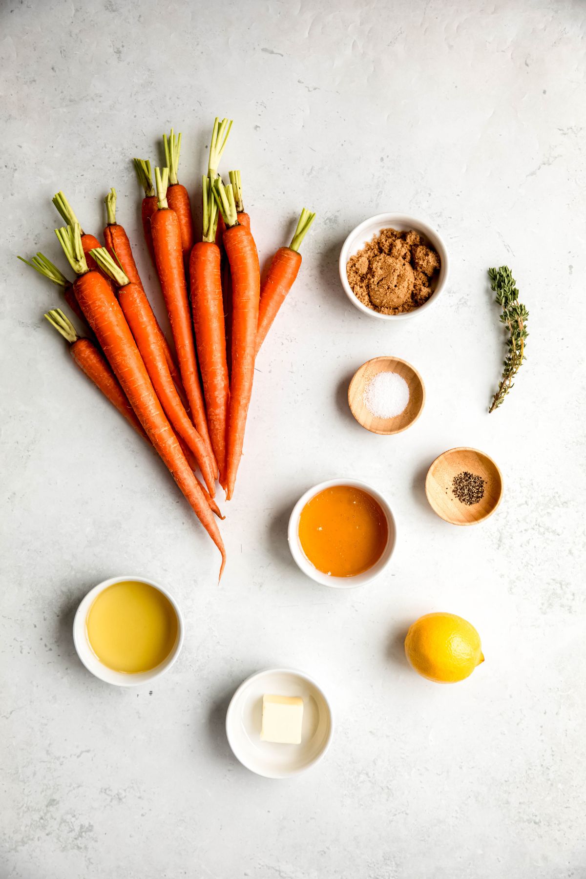 ingredients needed for making honey and brown sugar glazed carrots recipe measured out on a white table.