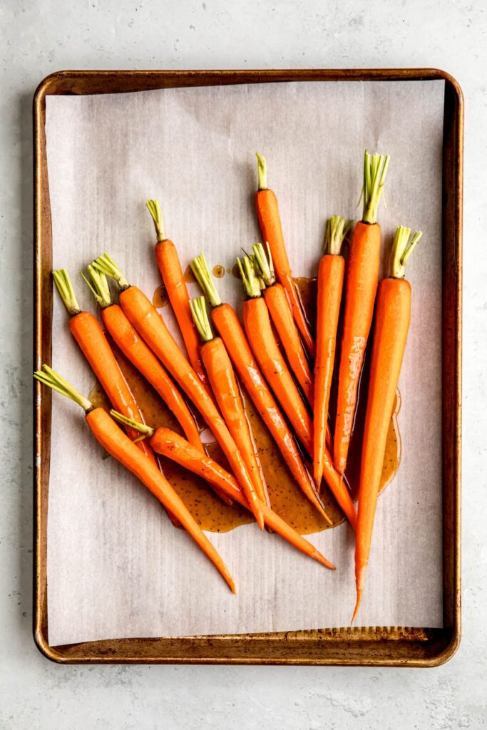 carrots on a parchment lined baking sheet and coated with the honey brown sugar glaze.