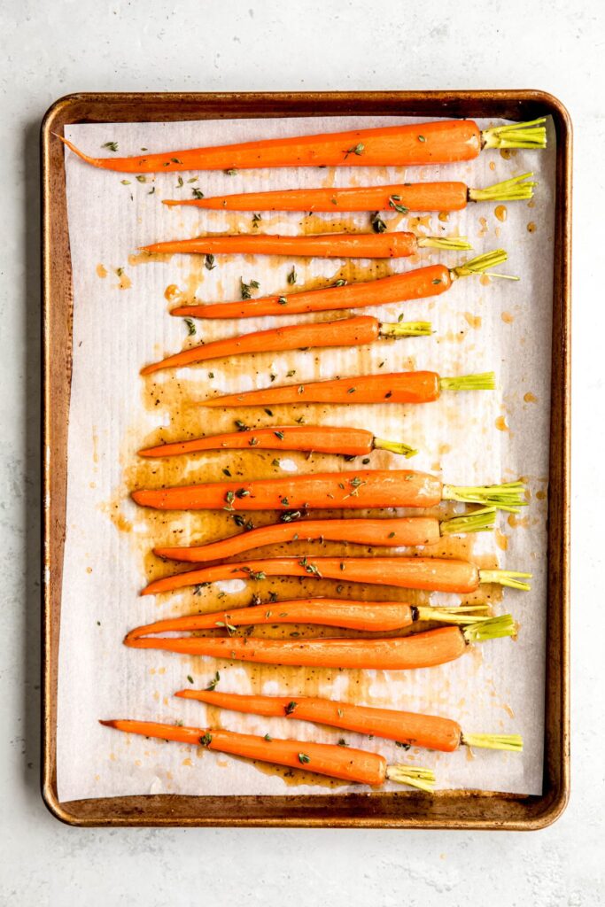 carrots lined up on the sheet pan after tossing with the glaze and spaced out to prevent steaming.