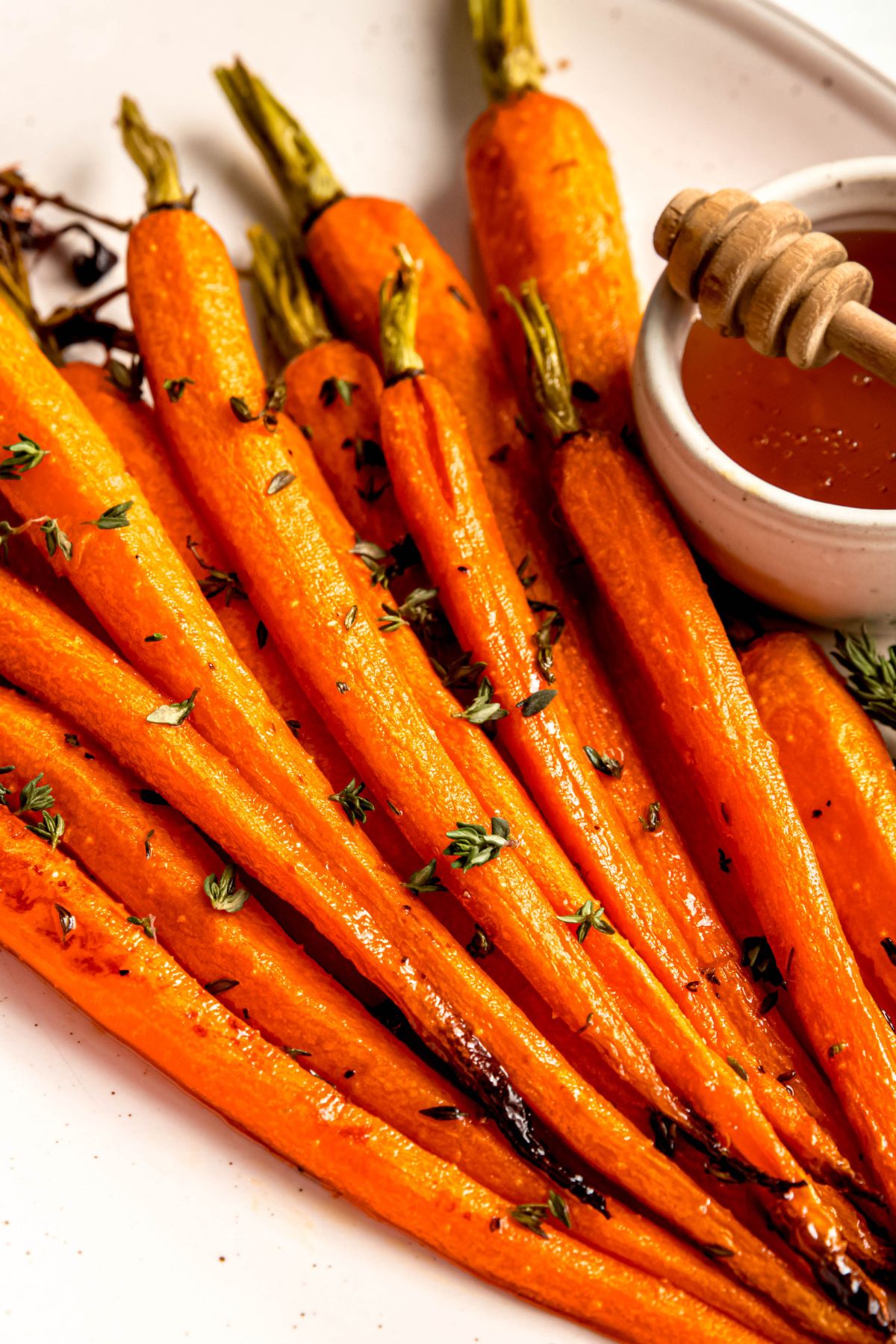 closeup overhead shot of brown sugar honey glazed carrots topped with thyme.