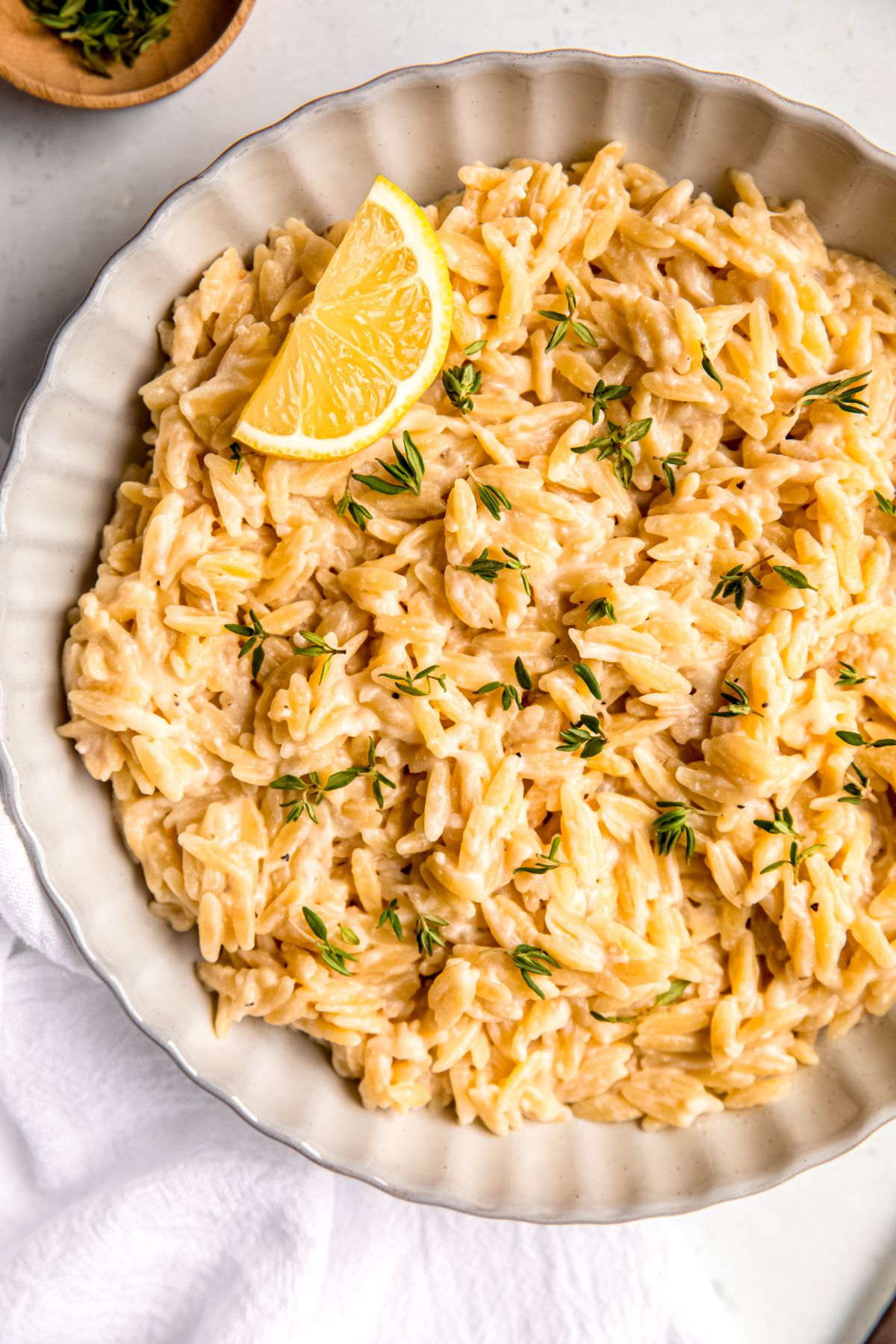 closeup overhead shot of a bowl of risotto-like lemon orzo one pot pasta topped with fresh thyme leaves.