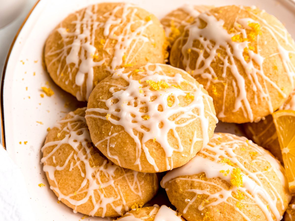 horizontally framed hero shot of a jumble of homemade lemon ricotta cookies with lemon glaze.