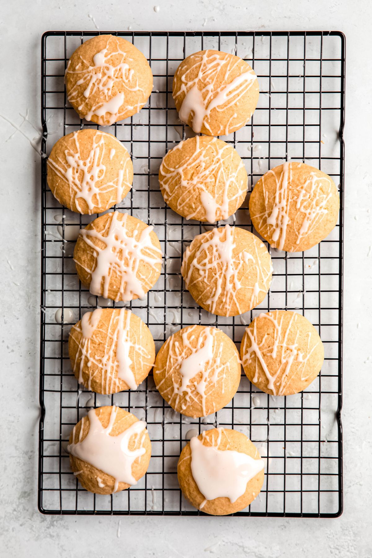 lemon ricotta cookies on a black wire cooling rack after cooling and drizzling with the lemon glaze.