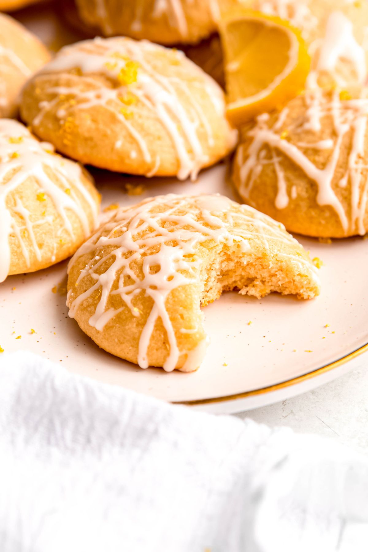 closeup shot of a ricotta lemon cookie with a bite taken out showing the cakey interior.