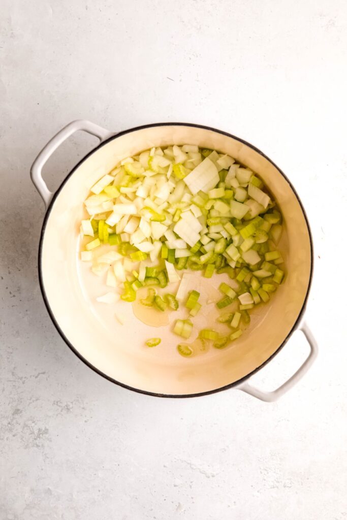 aromatics sauteing in oil in a white dutch oven.