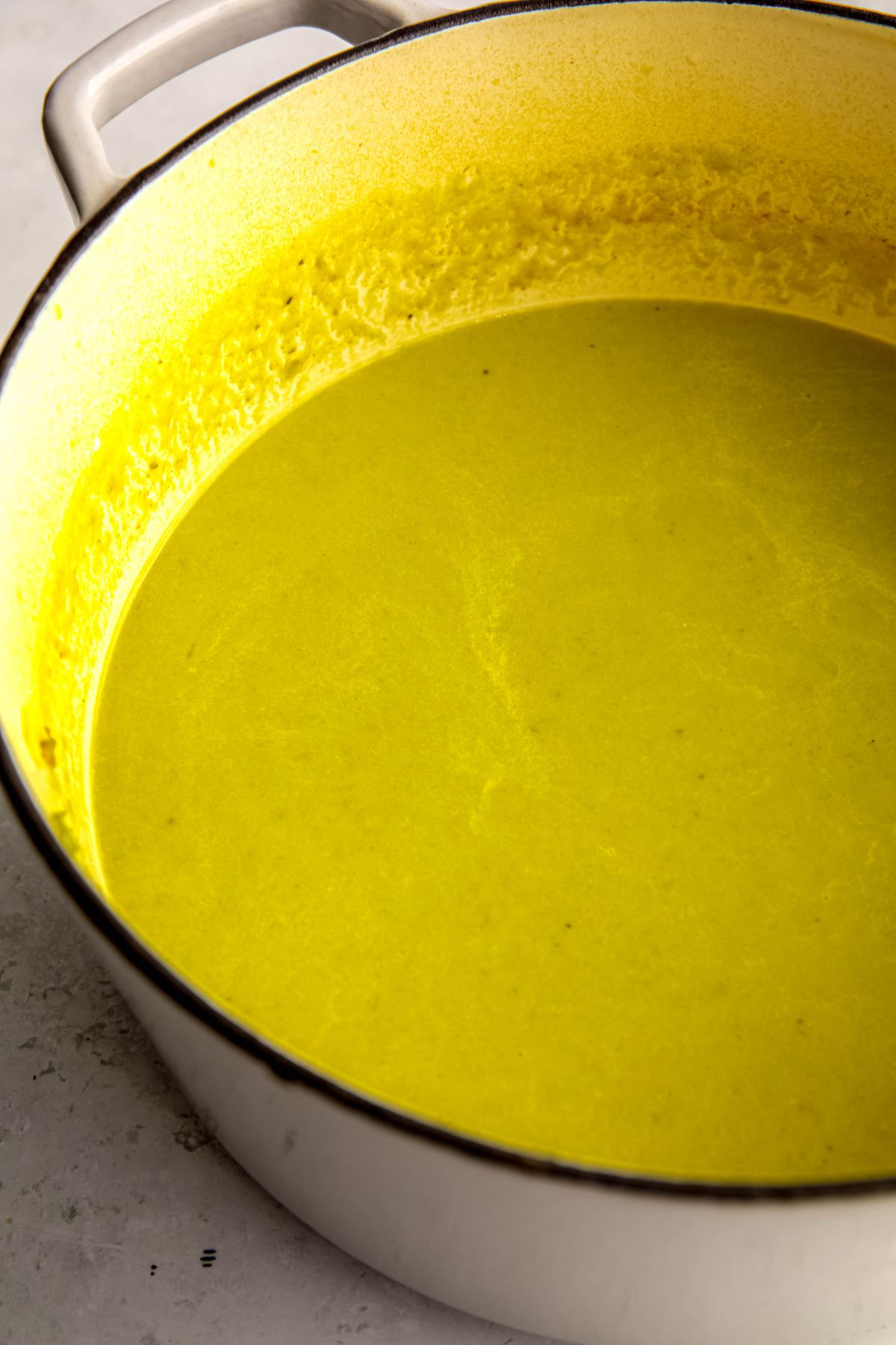 closeup shot of blended creamy asparagus soup in the white dutch oven after blending.