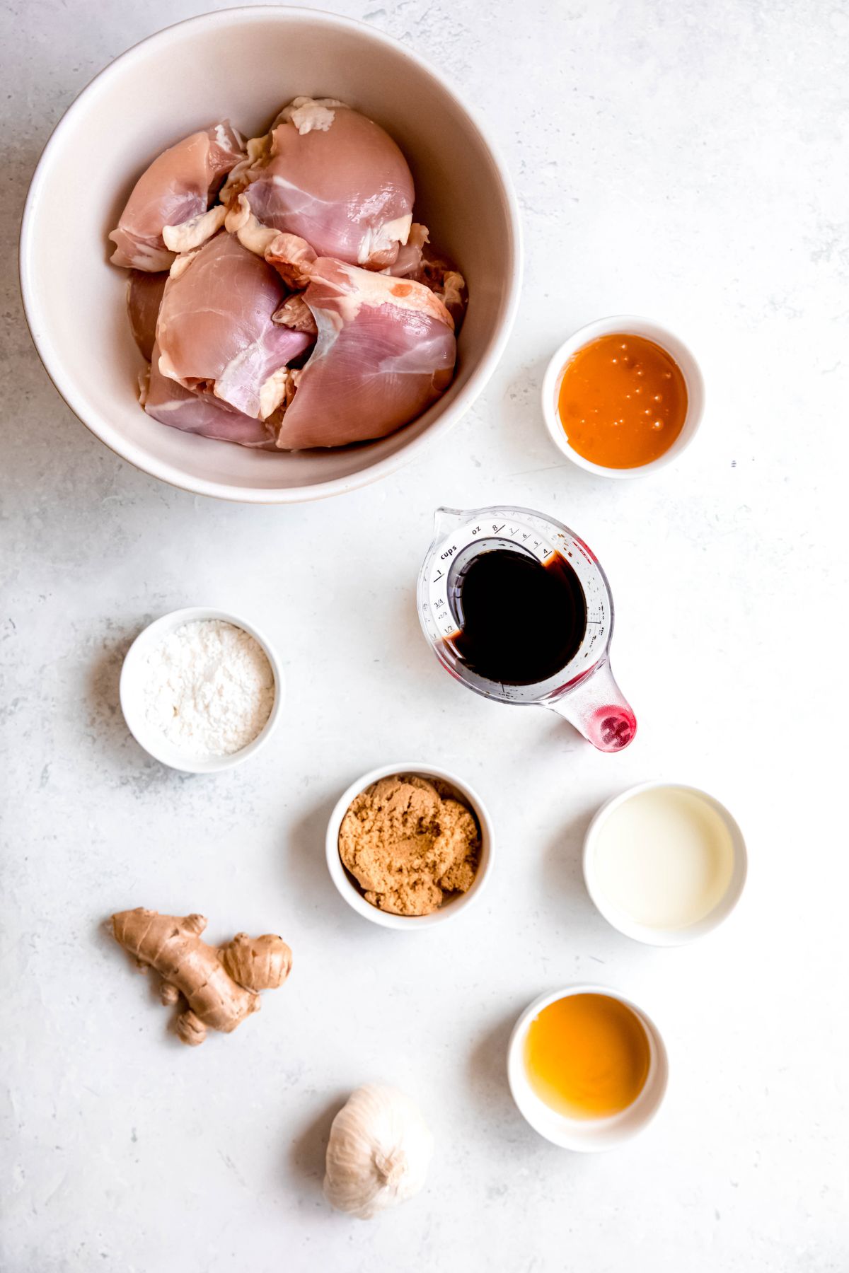 ingredients needed to make homemade grilled teriyaki chicken recipe measured out on a white table.