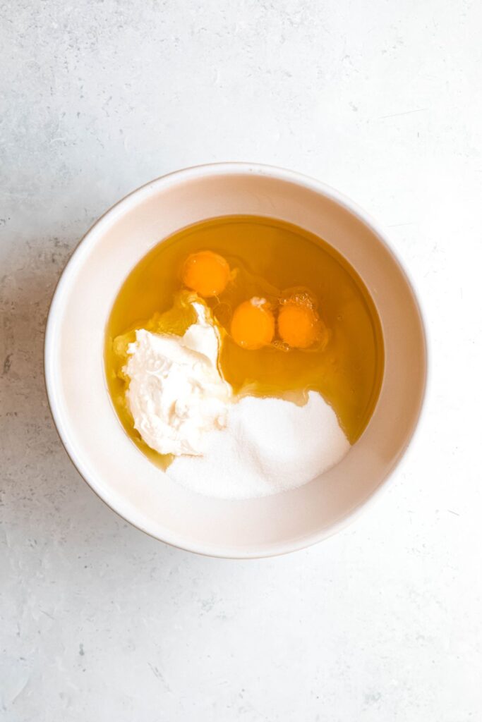 eggs, yogurt and sugar added to a mixing bowl.