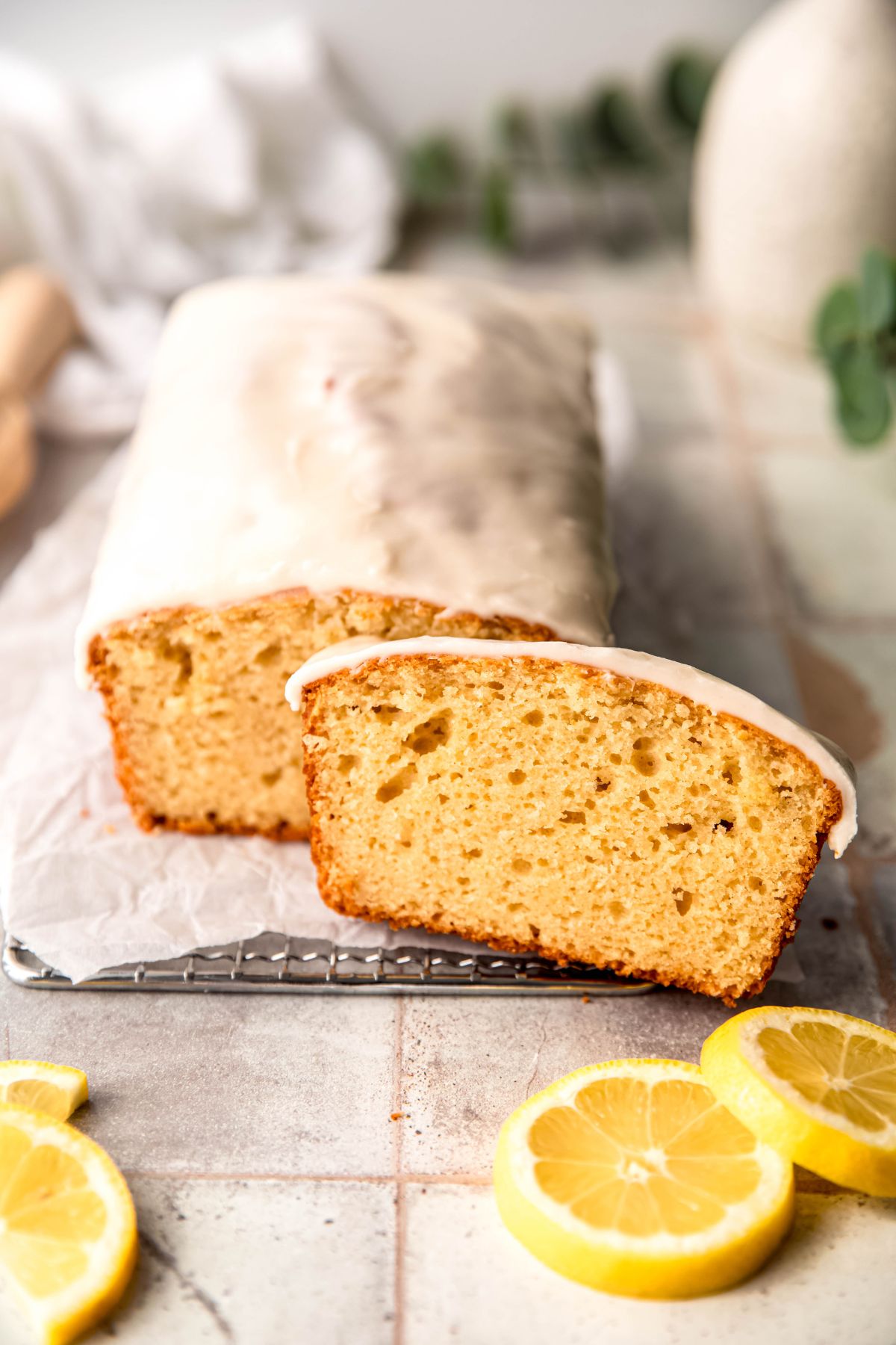 homemade Starbucks lemon loaf cake with a lemon glaze on a wire rack with one slice shifted slightly to the right of the rest of the cake.