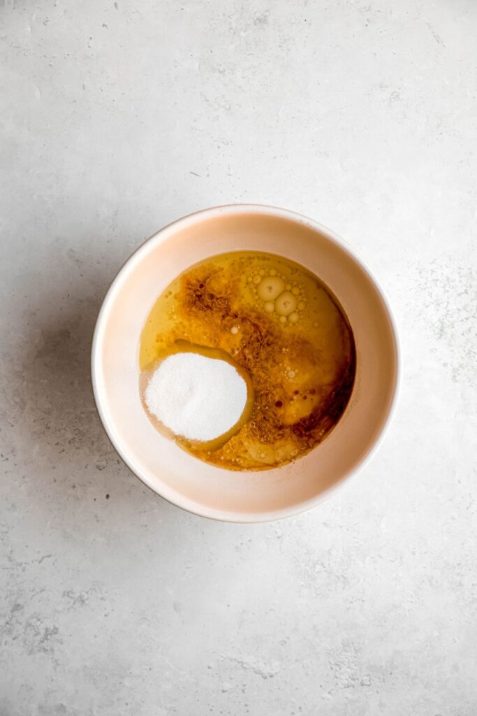 wet ingredients and sugar added to a mixing bowl.