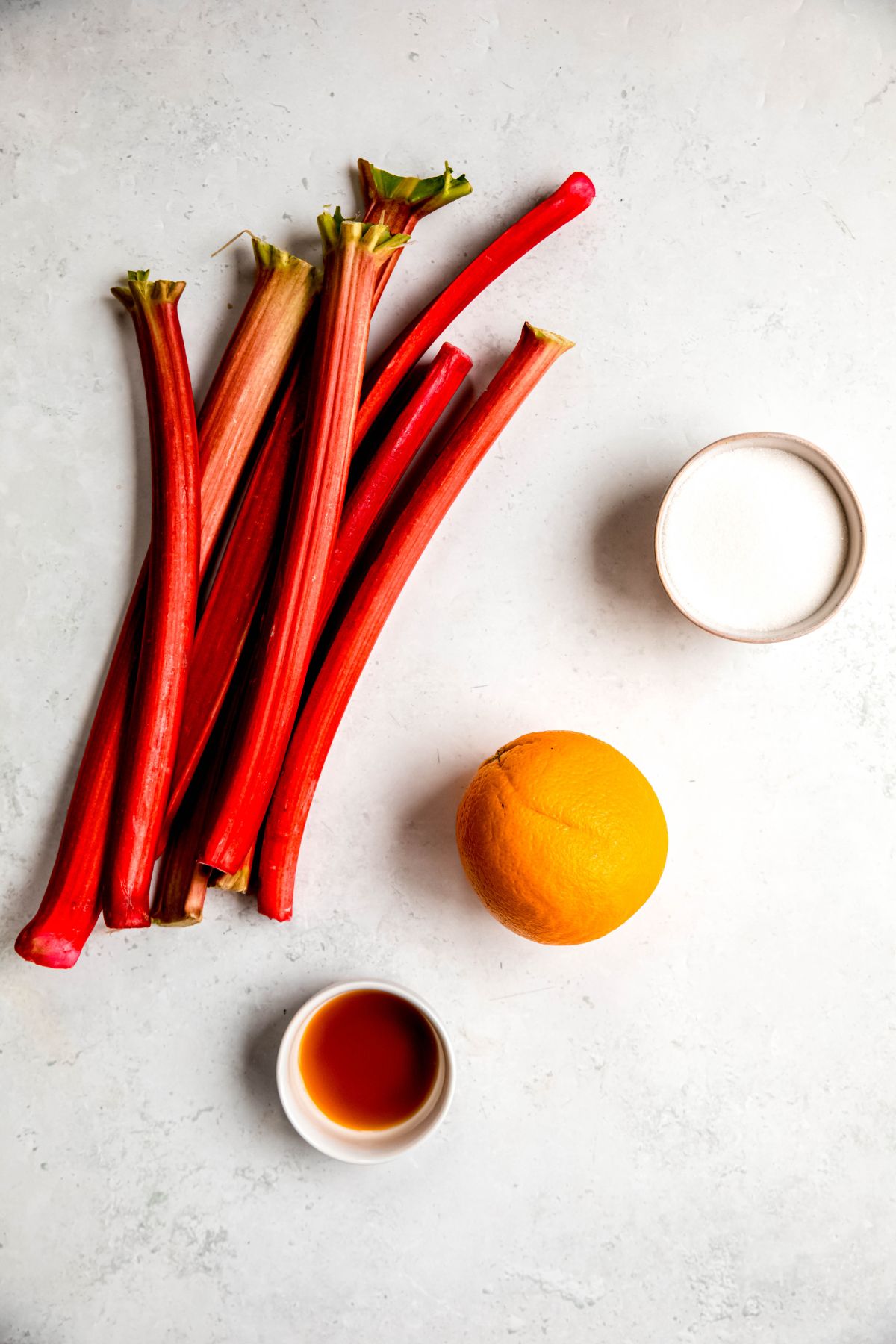overhead shot of ingredients needed to make easy rhubarb sauce recipe measured out on a white table.