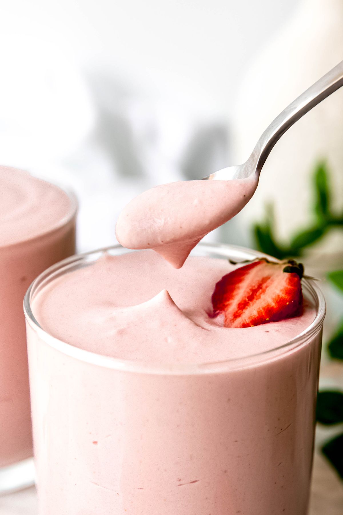 action shot of a silver spoon taking a bite of high protein strawberry mousse from a glass jar showing how light and thick it is.