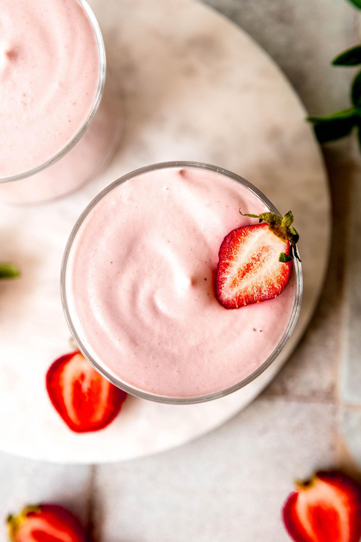 overhead shot of a glass of high protein strawberry mousse fluff topped with a halved strawberry.