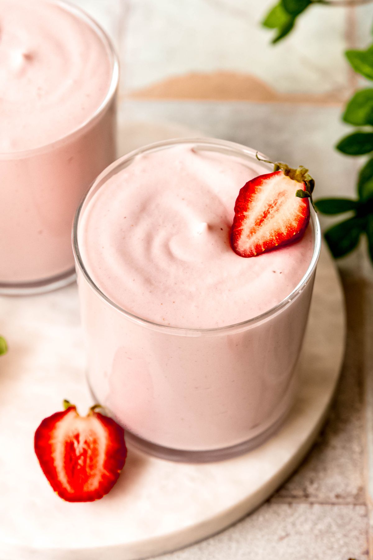 closeup 45 degree angle shot of two rocks glasses filled with healthy, mousse-like strawberry fluff made with cottage cheese and protein powder.